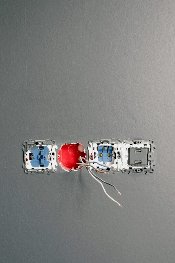 Sockets with wires and bolts on gray painted wall at home during construction